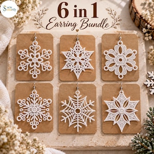 Könnte beinhalten: Ein 6-in-1-Ohrring-Set mit sechs verschiedenen weißen schneeflockenförmigen Ohrringen, die auf einzelnen braunen rechteckigen Karten präsentiert werden. Der Text 6 in 1 Earring Bundle steht oben auf dem Set mit einem kleinen Logo.