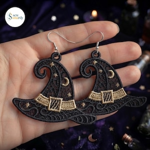 May include: A pair of black lace earrings shaped like witch hats with gold embroidered bands, buckles, and small star and crescent moon details. The earrings feature silver-toned metal hooks for attachment and have a delicate, intricate threadwork design.