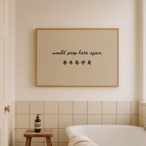 May include: A framed print with the text "would poop here again" and star graphics hangs above a bathtub. The bathroom has a neutral color palette with a wooden stool and a soap dispenser.
