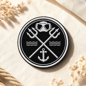 May include: Embroidered patch with a black background and white detailing. The design features crossed tridents, a diving mask, an anchor, and wavy lines, all within a circular border. The patch is likely for a diving or nautical theme.