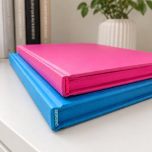A5 blue journal with blue interior pages and hardcover, shown fully open to demonstrate the sewn lay-flat binding, smooth writing pages, and modern minimalist stationery aesthetic.