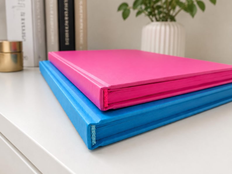 A5 blue journal with blue interior pages and hardcover, shown fully open to demonstrate the sewn lay-flat binding, smooth writing pages, and modern minimalist stationery aesthetic.