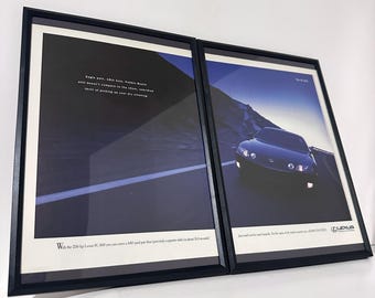 May include: Two framed Lexus car advertisements. One features a car on a road with text, the other has text and a dark blue background. The frames are black.