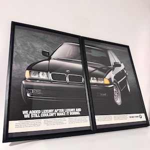 Könnte beinhalten: Zwei gerahmte Drucke mit einer schwarzen BMW Limousine. Das Auto steht im Mittelpunkt des Bildes, wobei die Front des Autos dem Betrachter zugewandt ist. Die Drucke haben einen schwarzen Rahmen und den Text: "WE ADDED LUXURY AFTER LUXURY AND WE STILL COULDN'T MAKE IT BORING."