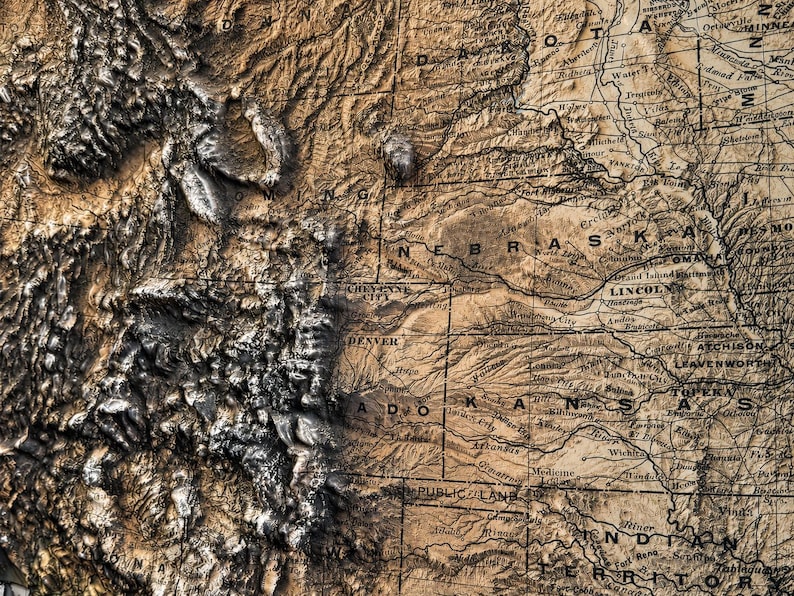 May include: A detailed, three-dimensional map of the central United States, featuring states like Nebraska, Kansas, and Colorado. The map has a vintage aesthetic with a brown and tan color palette, highlighting topographical features.