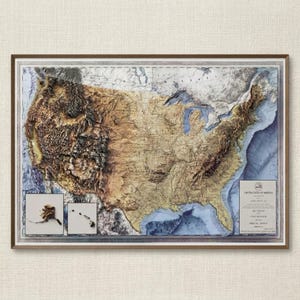 May include: A framed 3D relief map of the United States of America, showcasing the country's topography in shades of brown, tan, and blue. The map includes insets of Alaska and Hawaii. The frame is a light brown color.