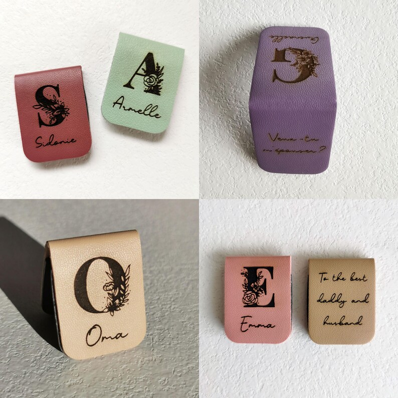 May include: A collection of rectangular magnetic bookmarks made of textured material in various colors including pink, light green, purple, beige, and tan. Each bookmark features a printed initial with floral accents and custom text.