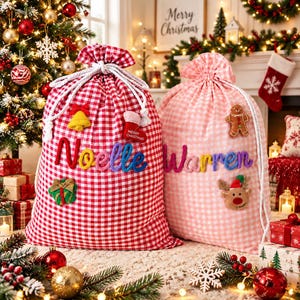 Puede incluir: Dos bolsas de regalo de tela con cordón y estampado de cuadros vichy. La bolsa izquierda es roja y blanca con el nombre Noelle en letras de lana de colores, una campana amarilla, un calcetín rojo y un regalo verde. La bolsa derecha es rosa y blanca con el nombre Warren en letras de lana de colores, un hombre de jengibre y un reno.