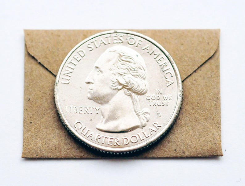 May include: A silver US quarter dollar coin with the image of George Washington on the front. The coin is on a brown paper envelope.