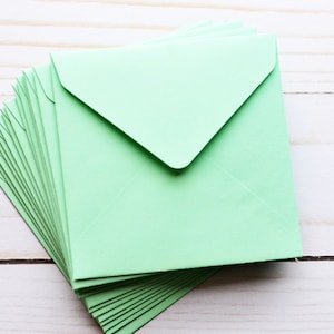 Peut inclure: Une pile d'enveloppes vert clair, pliées et prêtes à être utilisées pour envoyer des lettres ou des invitations.