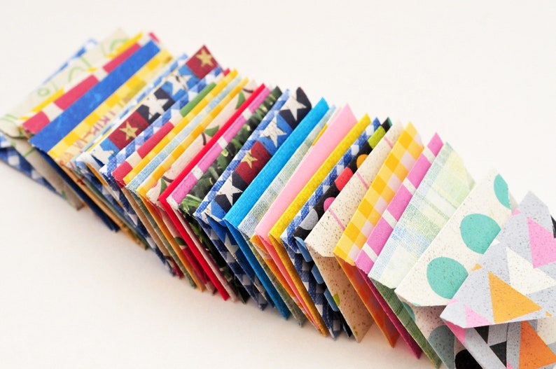 May include: A stack of colorful folded paper envelopes with various patterns, including stars, polka dots, stripes, and plaid.