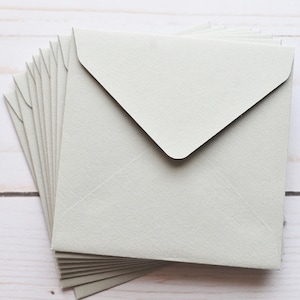 May include: A stack of light gray envelopes with a pointed flap.