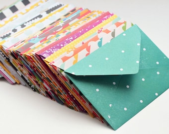 May include: A stack of colorful patterned envelopes with a teal envelope with white polka dots on top.
