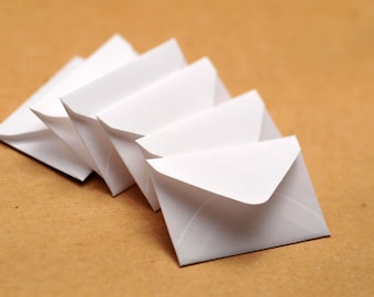 May include: A stack of white envelopes on a brown surface.