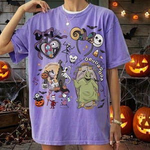 May include: A light purple t-shirt featuring a graphic print of characters and icons from The Nightmare Before Christmas, including Jack Skellington, Sally, Oogie Boogie, and Zero, arranged in a collage style with various Halloween motifs.