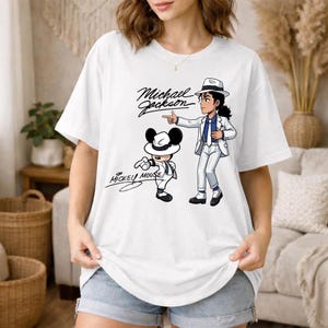 K&ouml;nnte beinhalten: Wei&szlig;es T-Shirt mit einer Cartoon-Illustration von Michael Jackson und Mickey Mouse. Das Design enth&auml;lt den Text "Michael Jackson" und "Mickey Mouse". Die Illustration zeigt beide Charaktere in &auml;hnlichen Outfits.