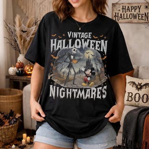 K&ouml;nnte beinhalten: Ein schwarzes Kurzarm-T-Shirt mit einem Grafikdruck und dem Text VINTAGE HALLOWEEN NIGHTMARES. Das Design zeigt Jack Skellington und Mickey Mouse in einer gruseligen Landschaft mit Schloss, Flederm&auml;usen und Vollmond, inklusive des Textes EST. 1937.