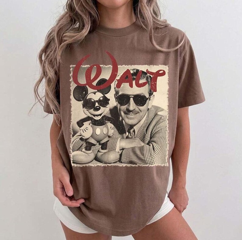 May include: Brown t-shirt featuring a vintage graphic of Walt Disney and Mickey Mouse wearing sunglasses. The word "Walt" is in red script above the image. The shirt has a classic, relaxed fit.