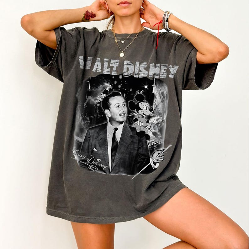 Peut inclure: T-shirt gris fonc&eacute; avec un imprim&eacute; noir et blanc de Walt Disney et Mickey Mouse. Le texte "WALT DISNEY" est imprim&eacute; en haut. Le t-shirt a des manches courtes et une coupe ample.