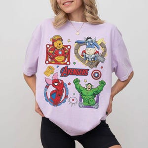 Puede incluir: Camiseta de color lila claro con un dise&ntilde;o de dibujos animados de los personajes de los Vengadores. El dise&ntilde;o incluye a Iron Man como Winnie the Pooh, a Thor como un burro, a Spider-Pig como Spider-Man y a Hulk. La palabra "Avengers" est&aacute; impresa en azul.