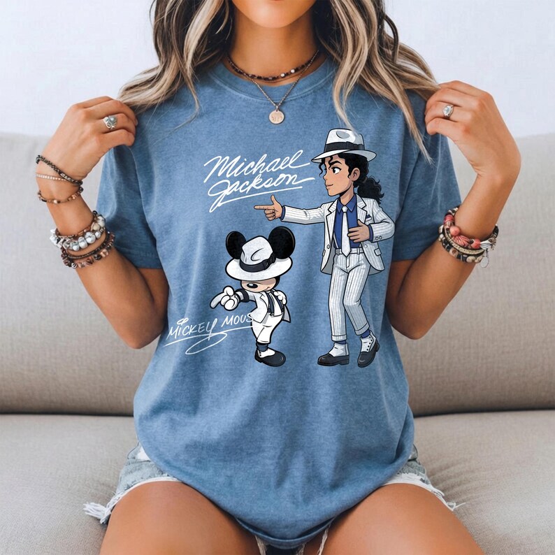 K&ouml;nnte beinhalten: Hellblaues T-Shirt mit einer Cartoon-Illustration von Michael Jackson und Mickey Mouse in passenden wei&szlig;en Anz&uuml;gen und H&uuml;ten. Der Text "Michael Jackson" und "Mickey Mouse" ist ebenfalls auf dem Shirt aufgedruckt.