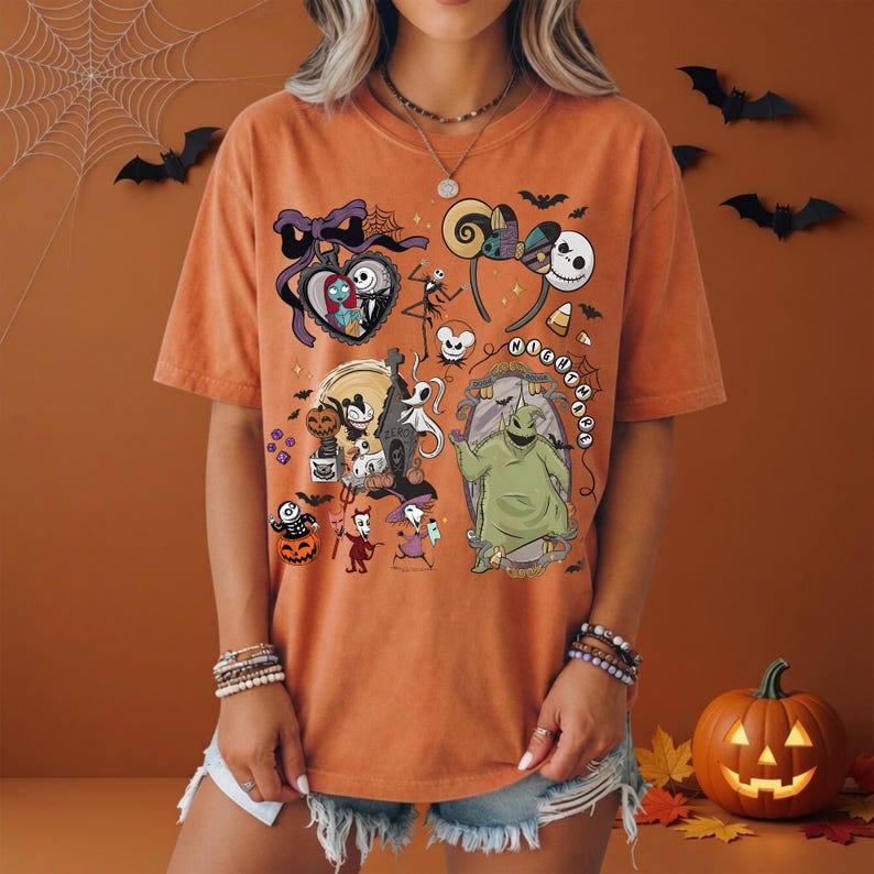 May include: An orange short-sleeve t-shirt featuring a graphic print of characters from The Nightmare Before Christmas, including Jack Skellington, Sally, Oogie Boogie, and Zero, along with various Halloween-themed icons and the text Nightmare.