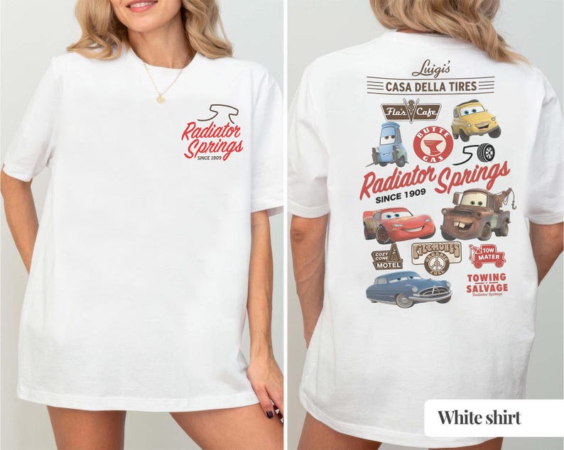 May include: A white t-shirt featuring a small Radiator Springs logo on the front left chest. The back displays a large graphic with various Cars characters, including Lightning McQueen and Mater, alongside text reading Luigi's Casa Della Tires.