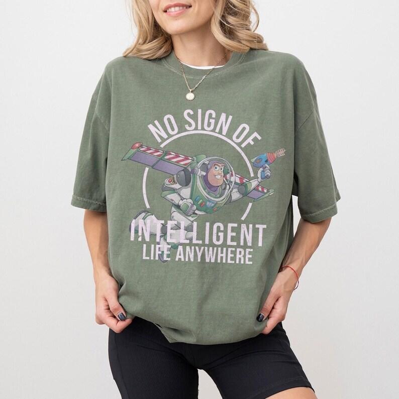 Pu&ograve; includere: T-shirt verde oliva con grafica di Buzz Lightyear in volo e la scritta bianca &laquo;NO SIGN OF INTELLIGENT LIFE ANYWHERE&raquo;. La maglietta ha maniche corte e una vestibilit&agrave; ampia, adatta per l'uso quotidiano.