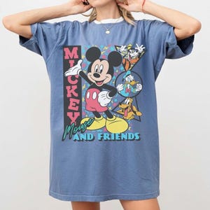 May include: A blue t-shirt featuring Mickey Mouse and friends. The graphic includes Mickey Mouse, Goofy, Donald Duck, and Pluto. The text "Mickey Mouse and Friends" is also displayed on the shirt.