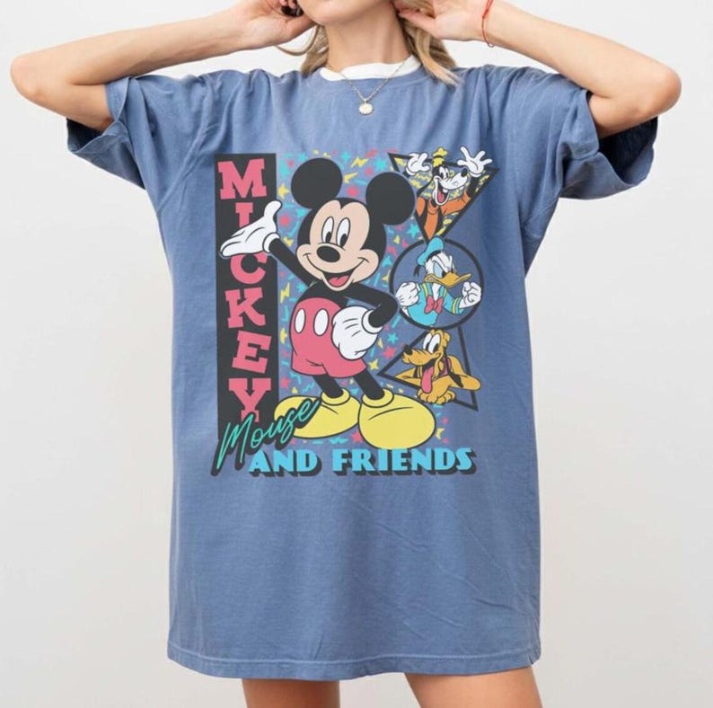 May include: A blue t-shirt featuring Mickey Mouse and friends. The graphic includes Mickey Mouse, Goofy, Donald Duck, and Pluto. The text "Mickey Mouse and Friends" is also displayed on the shirt.