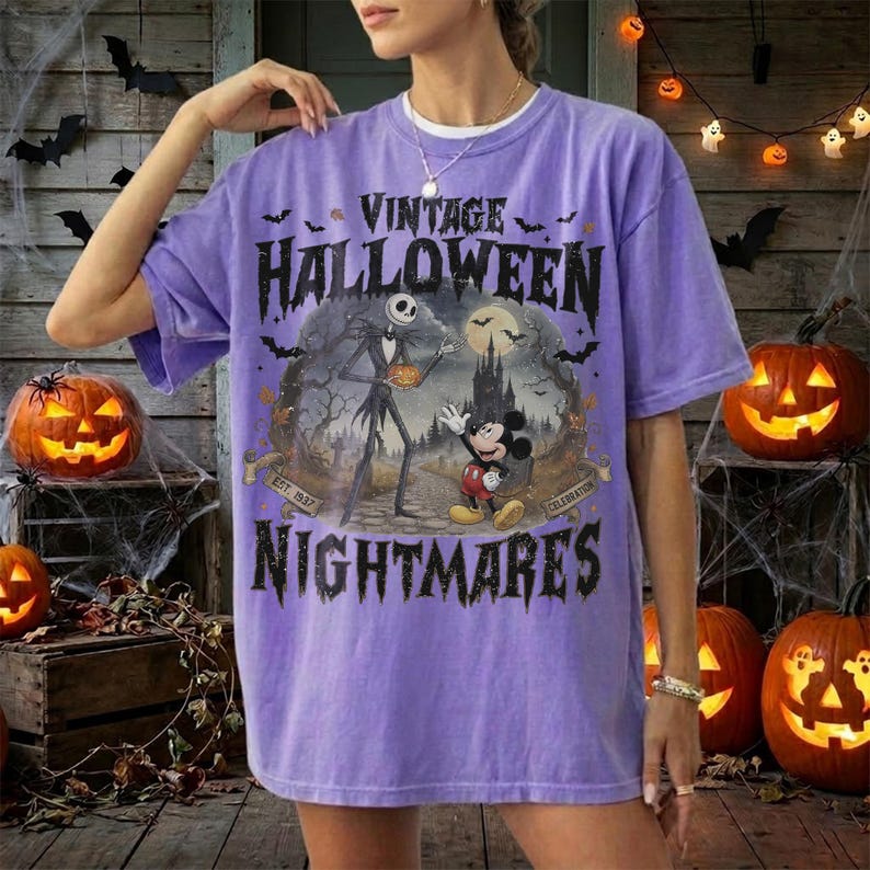 K&ouml;nnte beinhalten: Ein hellviolettes Kurzarm-T-Shirt mit einem Grafikdruck von Jack Skellington und Mickey Mouse. Der Text lautet VINTAGE HALLOWEEN NIGHTMARES und EST. 1937 CELEBRATION. Das Design zeigt ein dunkles Schloss, Flederm&auml;use und einen Vollmond.