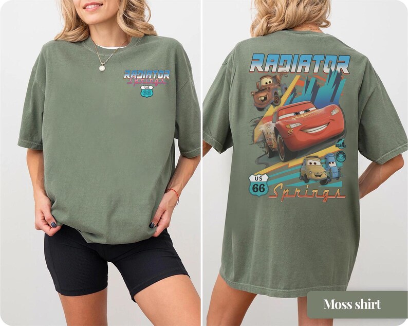 May include: An olive green t-shirt featuring a small Radiator Springs US 66 logo on the front chest. The back displays a large graphic of Lightning McQueen, Mater, and other characters with the text Radiator Springs and a US 66 road sign.