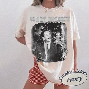 Peut inclure: T-shirt ivoire avec un graphisme en noir et blanc de Walt Disney et Mickey Mouse. Le texte "WALT DISNEY" est imprim&eacute; en haut. Le t-shirt est de la marque Comfort Colors.