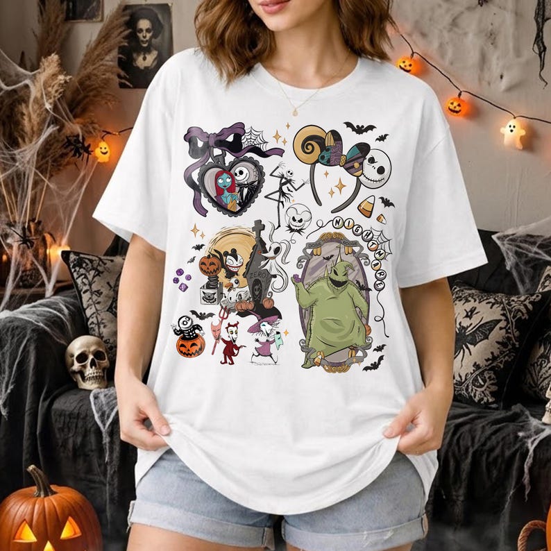 May include: A white short-sleeve t-shirt featuring a colorful graphic print of characters and icons from The Nightmare Before Christmas, including Jack Skellington, Sally, Oogie Boogie, Zero, and various Halloween-themed elements like pumpkins.