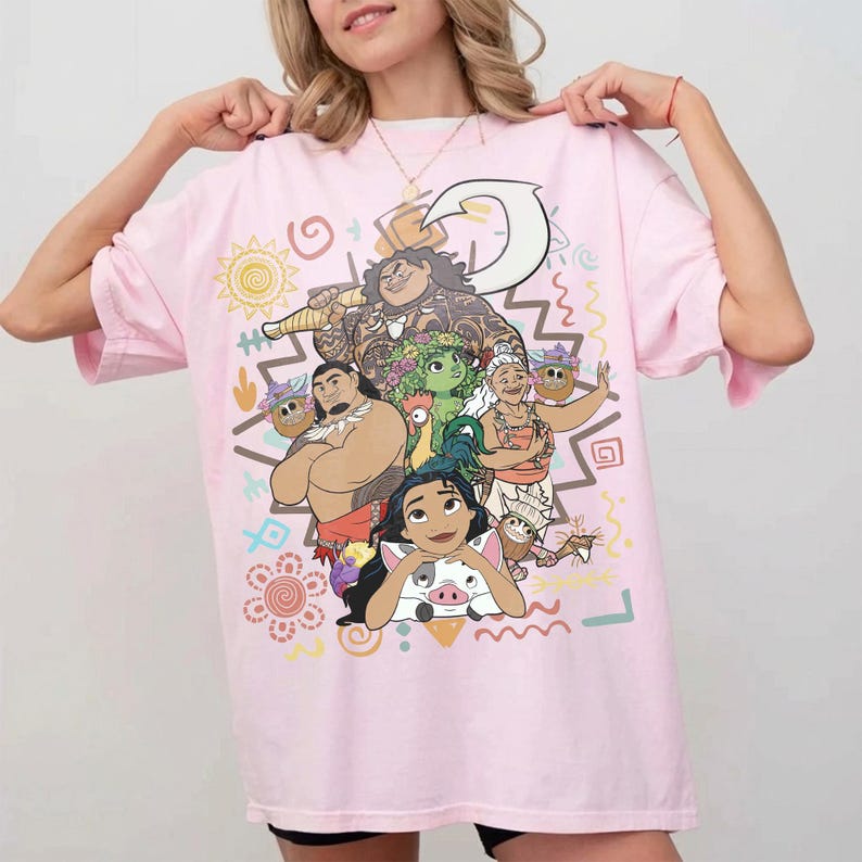 May include: A light pink short-sleeve t-shirt featuring a colorful graphic print of various animated characters, including a large figure with a hook, a woman, a pig, and smaller creatures, surrounded by stylized sun, flower, and wave symbols.