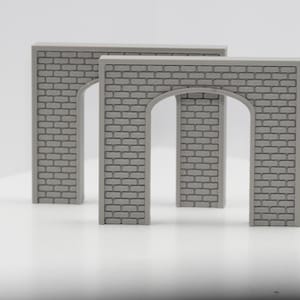 May include: Two gray, arched brick structures. The structures are rectangular with an arched opening in the center. The brick pattern is detailed, and the structures are set against a white background. These are likely model train or diorama accessories.