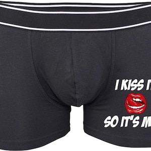 Puede incluir: Bóxers negros con cintura blanca y negra. El texto "I KISS IT SO IT'S MINE" está impreso en blanco, con un gráfico de labios rojos debajo.