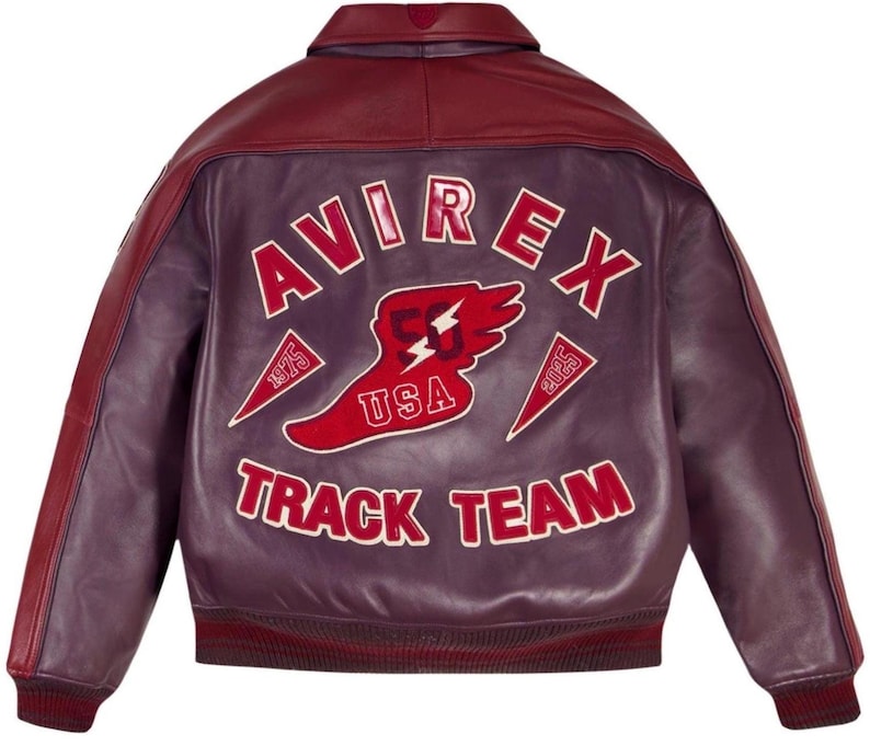 Pode incluir: Casaco de couro bord&ocirc; com gola e mangas marrons. As costas apresentam o texto "AVIREX TRACK TEAM" em letras brancas com detalhes em vermelho. Tamb&eacute;m est&aacute; presente um gr&aacute;fico vermelho e branco de um p&eacute; alado e um raio.