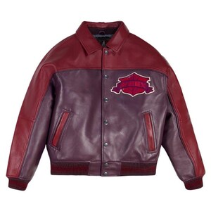 Pode incluir: Casaco de couro bord&ocirc; e roxo com gola e fecho de bot&otilde;es. O casaco apresenta um patch no peito com o texto "AVIREX". Punhos e bainha canelados. Um estilo cl&aacute;ssico de jaqueta bomber.