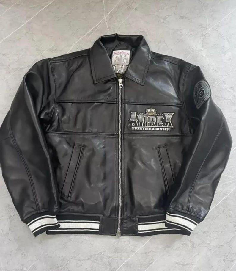 May include: Black leather jacket with a zip-up front, collar, and white striped cuffs and hem. The jacket features the "AVIREX" logo on the chest and a patch with the number "5" on the sleeve. A classic outerwear piece.