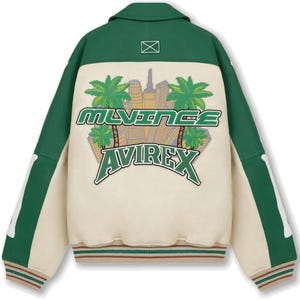 May include: Green and cream-colored bomber jacket with a button-down collar. The back features an embroidered design with palm trees, a cityscape, and the text "MLVINCE AVIREX" in green. The jacket has green sleeves and a striped hem.