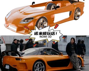 Op de afbeelding: Oranje sportwagenmodel met een spoiler en zilveren velgen. De auto is een replica van een echt voertuig. De afbeelding toont ook een scène met de auto in een straatomgeving. De tekst "NOMI 3D" is zichtbaar.