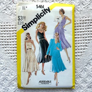 May include: Vintage Simplicity sewing pattern number 5461 for size 10 miss. The pattern includes four different dress styles: a white dress with a black belt, a black dress with a white belt, a blue dress with a matching jacket, and a lavender dress with a white belt. The pattern is adjustable for miss petite.