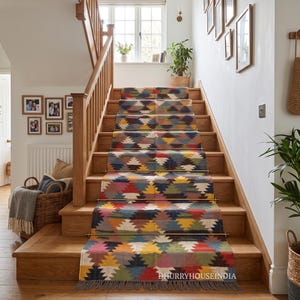 Puede incluir: Una alfombra larga y multicolor para escaleras con un patrón geométrico repetitivo de diamantes en tonos rojo, amarillo, azul y verde. La alfombra está fijada a los escalones de madera con varillas metálicas y tiene flecos en el borde.