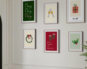 May include: A collection of six framed art prints with a Christmas theme. The prints feature festive illustrations and text, including a green print with "Merry Merry Merry", a gift, champagne glasses, and a wreath. The frames are a light wood color.