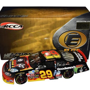 Op de afbeelding: Een zwart, rood en geel gegoten model raceauto met het nummer 29 op de zijkant, gepresenteerd voor de originele doos. De auto heeft sponsorlogo's en de tekst "Goodwrench" en "KISS". De doos heeft het "RCCA"-logo.