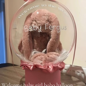 May include: A white ceramic mug with a black handle and the text "But First, Coffee" in a black, handwritten-style font. The mug is on a white surface.