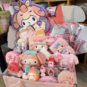Pode incluir: Uma caixa de presente cheia de vários artigos de papelaria e acessórios com o tema My Melody, incluindo peluches, pequenas bolsas, canetas, autocolantes e itens decorativos. A coleção apresenta cores rosa e pastel com motivos de personagens.