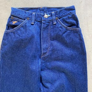 May include: A pair of dark blue denim jeans with a small horse logo on the left pocket.