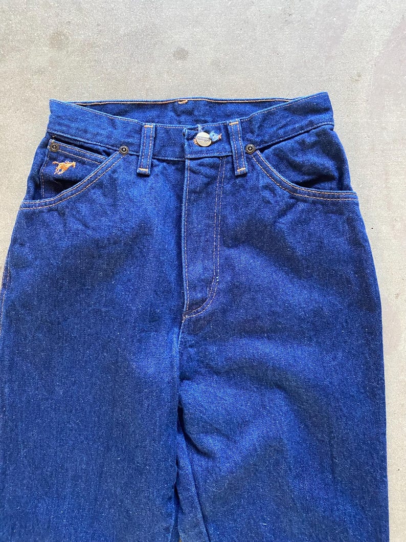 May include: A pair of dark blue denim jeans with a small horse logo on the left pocket.